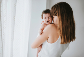 Madre sostiene en brazos a su bebé llorando