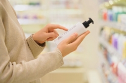 Mujer lee etiqueta de un producto cosmético