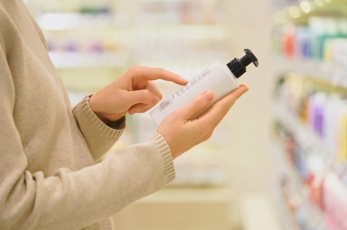 Mujer lee etiqueta de un producto cosmético